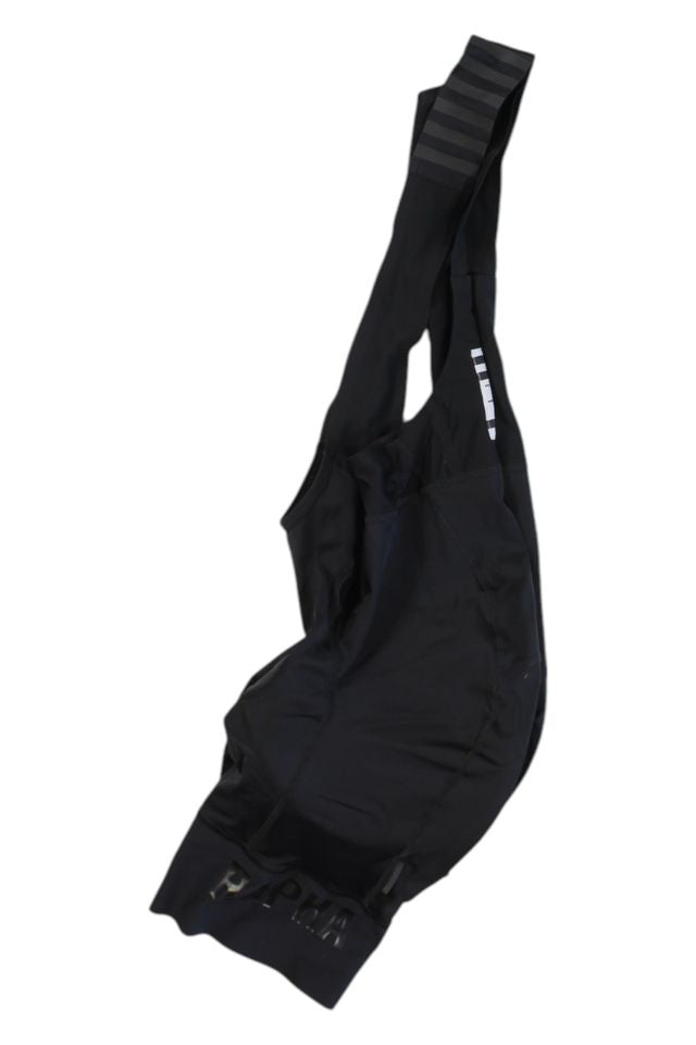 A pair of Rapha Mens Pro Team Bib Shorts II - Regular with shoulder straps, subtle branding, minimalist design, and a race-grade chamois is laid flat on a white background.