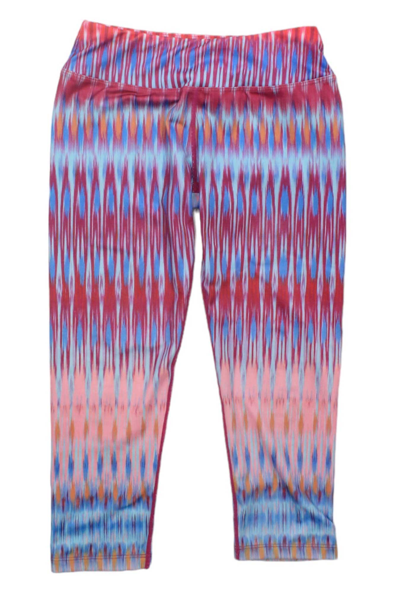 The Womens Roxanne Capris feature a bold, ikat-inspired pattern with red, blue, and peach horizontal stripes. Made from micropoly performance jersey for top yoga comfort, these cropped leggings are shown flat on a white background.