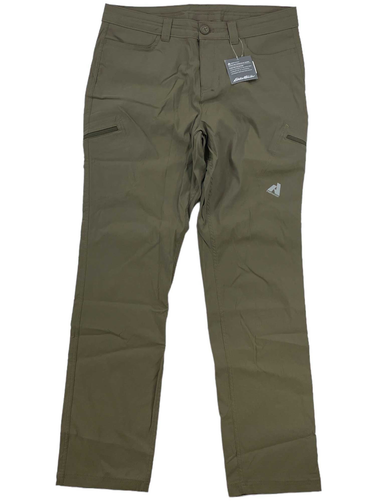 Eddie Bauer First Ascent Women's Guide Pro Pant in olive green features zippered thigh pockets, button and zip closure, belt loops, a small logo on the upper left leg, water-resistant and sun-protective fabric, plus a tag near the waistband.
