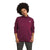 A person with short curly hair wears The North Face Womens Canyonlands Pullover Tunic, a maroon, long-sleeve stretch fleece with a high collar and left chest logo, standing against a plain white background.