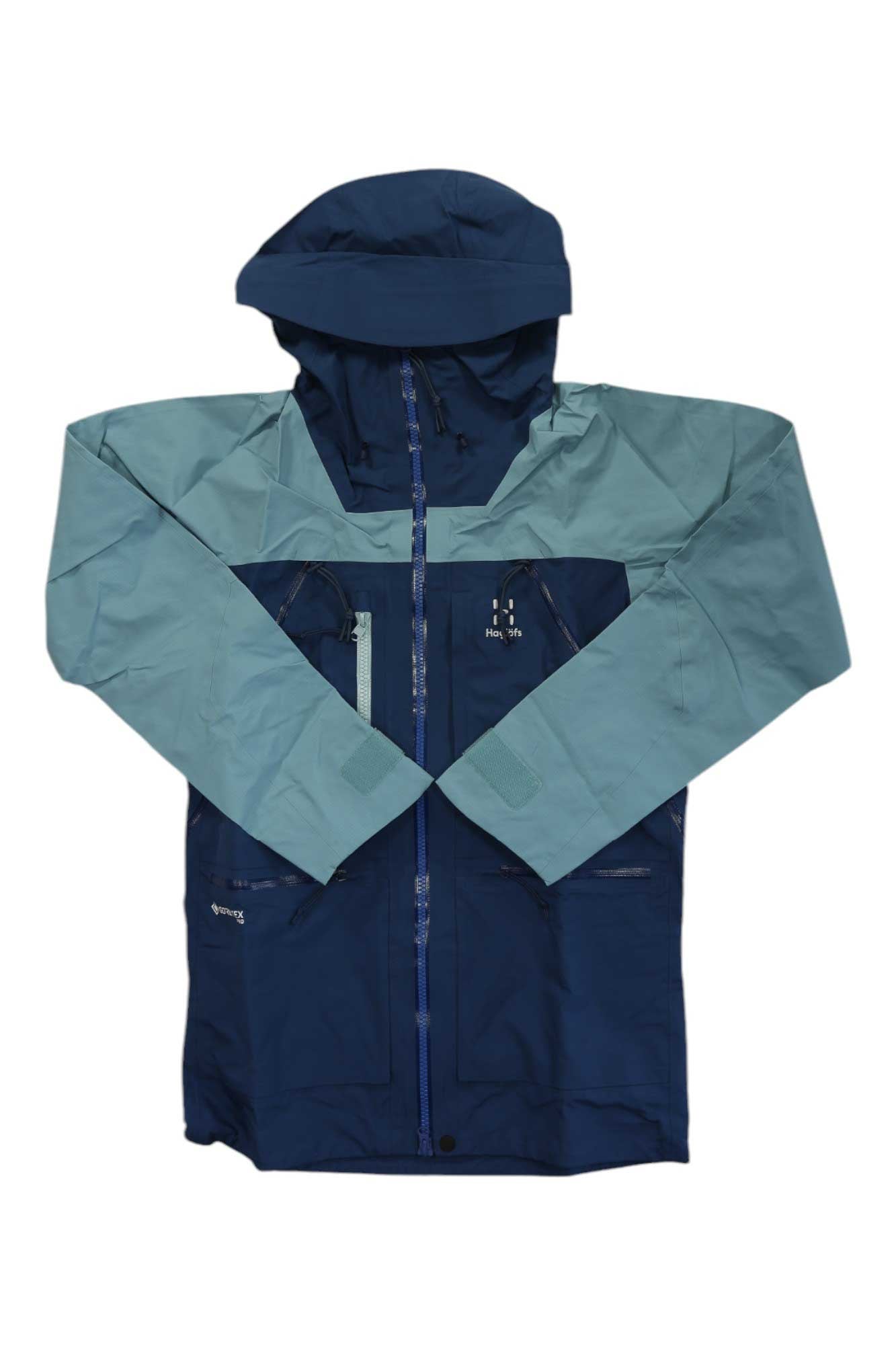 The Haglofs Men's Vassi GTX Pro Jacket is a two-tone freeride ski jacket with dark blue on the lower body and sleeves, light blue on the upper chest, arms, and hood. It features a front zipper, multiple zippered pockets, and is inspired by GORE-TEX Pro design.