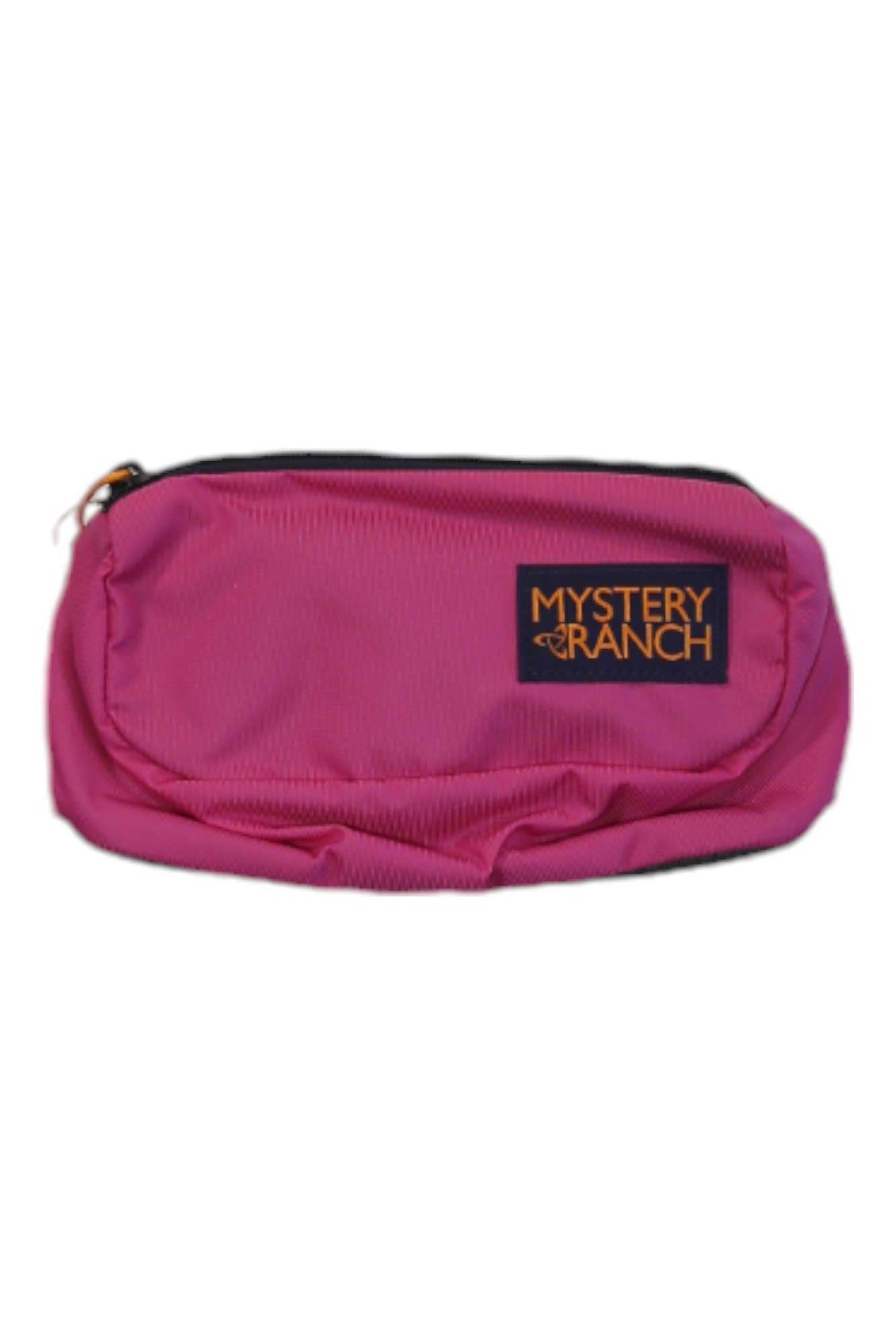 The Mystery Ranch Forager Hip Pack in pink features a black logo patch on the front and is shown against a white background—ideal for carrying essentials on your outdoor adventures.