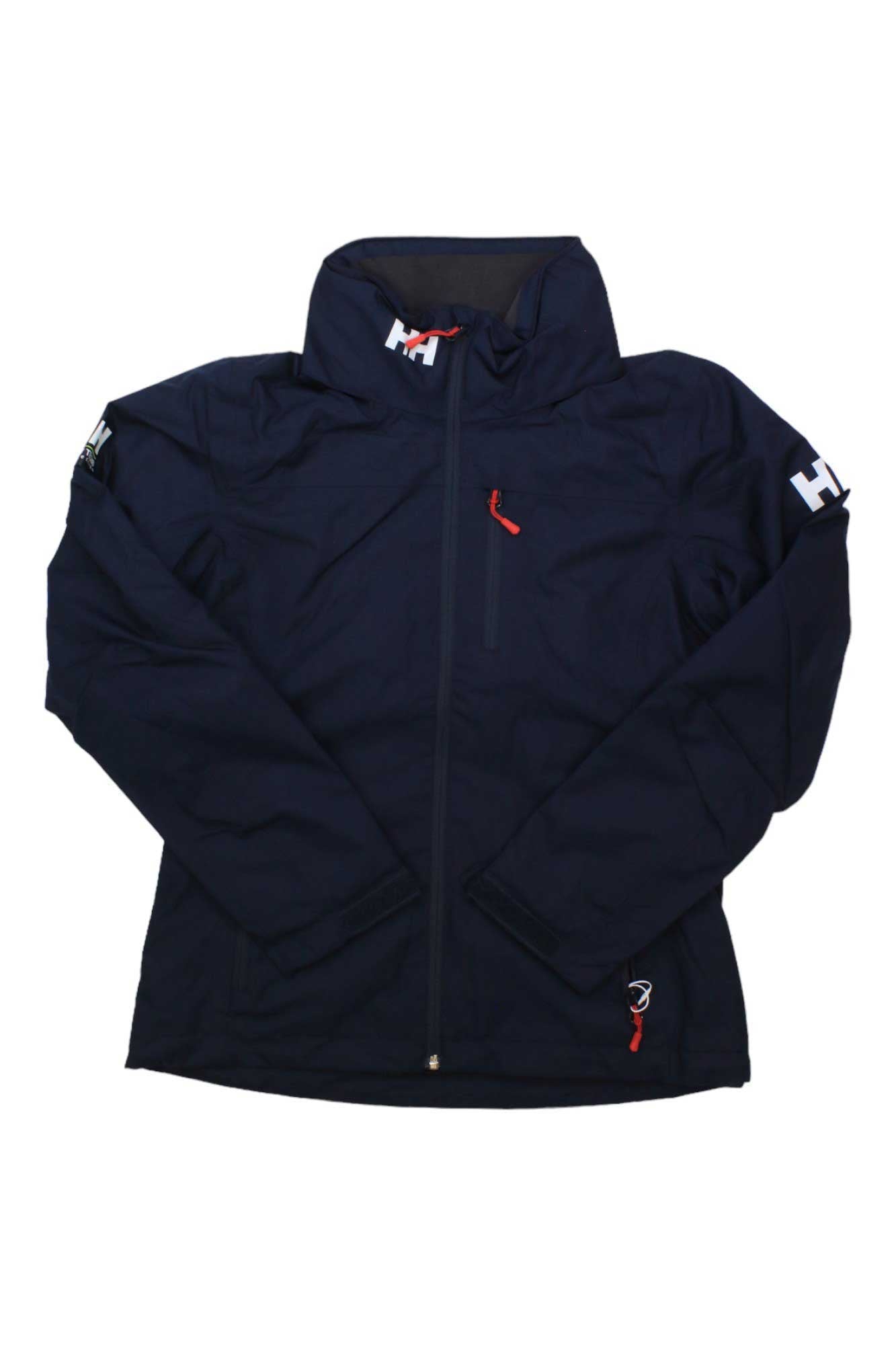 The Helly Hansen Womens Crew Hooded Midlayer Jacket is a navy blue fleece midlayer for women, featuring a high collar, red zipper pulls, white HH logos on the collar and left sleeve, and made from cozy Polartec fleece.