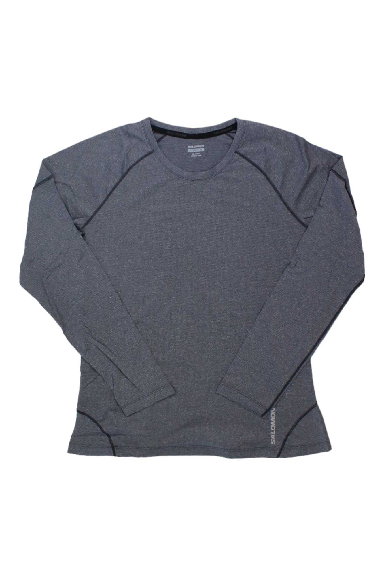 The Salomon Womens Cross Run LS Tee in dark gray is laid flat on a white background. With a crew neck and subtle seams at the shoulders and sides, this lightweight, breathable long sleeve shirt is perfect for quick drying during active workouts.
