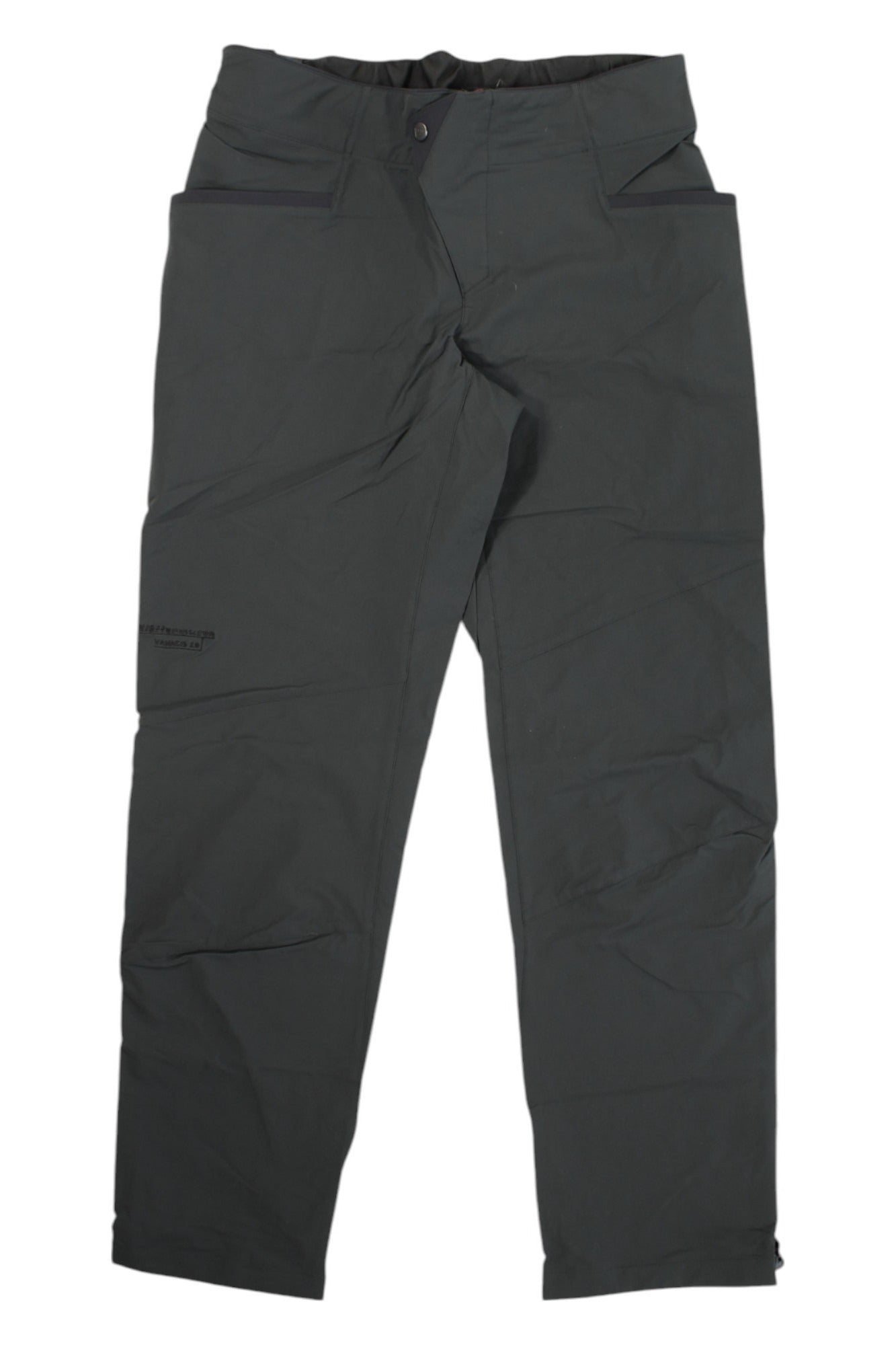 The Klattermusen Womens Vanadis 2.0 Traverse Pant is a pair of dark gray, straight-leg trekking trousers with front pockets and a button closure, shown laid flat on a white background.