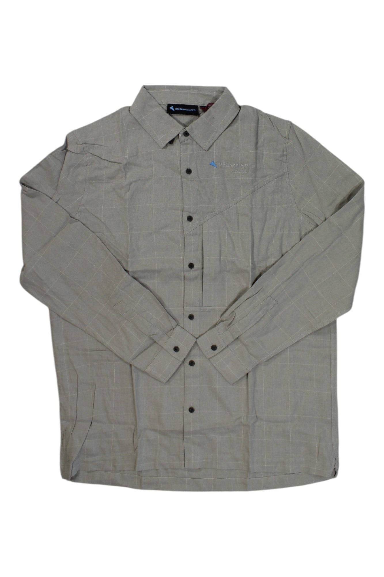 The Klattermusen Mens Helheim LS Shirt is a long-sleeve, light gray plaid outdoor shirt with a collar, black buttons, a subtle checked pattern, and moisture-wicking fabric for comfort. Shown laid flat with sleeves crossed.