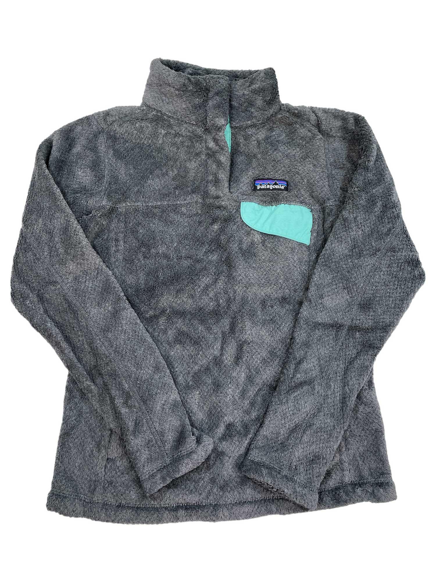The Women's Re-Tool Snap-T Pullover is a gray Polartec Thermal Pro fleece with a stand-up collar, turquoise chest pocket, and Patagonia logo patch. This relaxed-fit, long-sleeve top is Fair Trade Certified for ethical production.