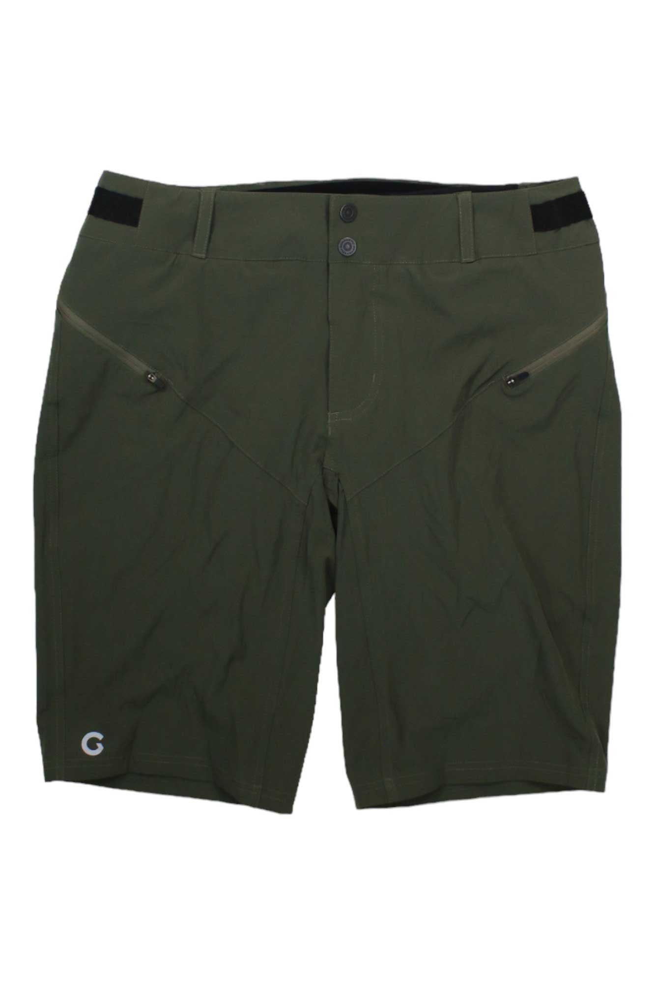 The Louis Garneau Womens Latitude 2 Short features an olive green, knee-length design with front zippered pockets, adjustable waist, black waistband accents, and a small white G logo on the lower left leg. Shown on a white background.