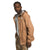 A man wears The North Face Men's Alta Vista Jacket, a tan hooded waterproof jacket made from recycled fabrics, along with camouflage pants, looking toward the camera against a plain white background.