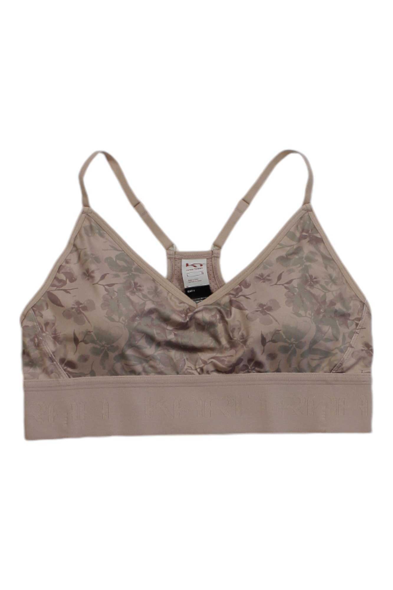 The Kari Traa Womens Var Printed Sports Bra in tan features a subtle floral pattern, thin adjustable straps, and a wide branded band at the bottom for light support.
