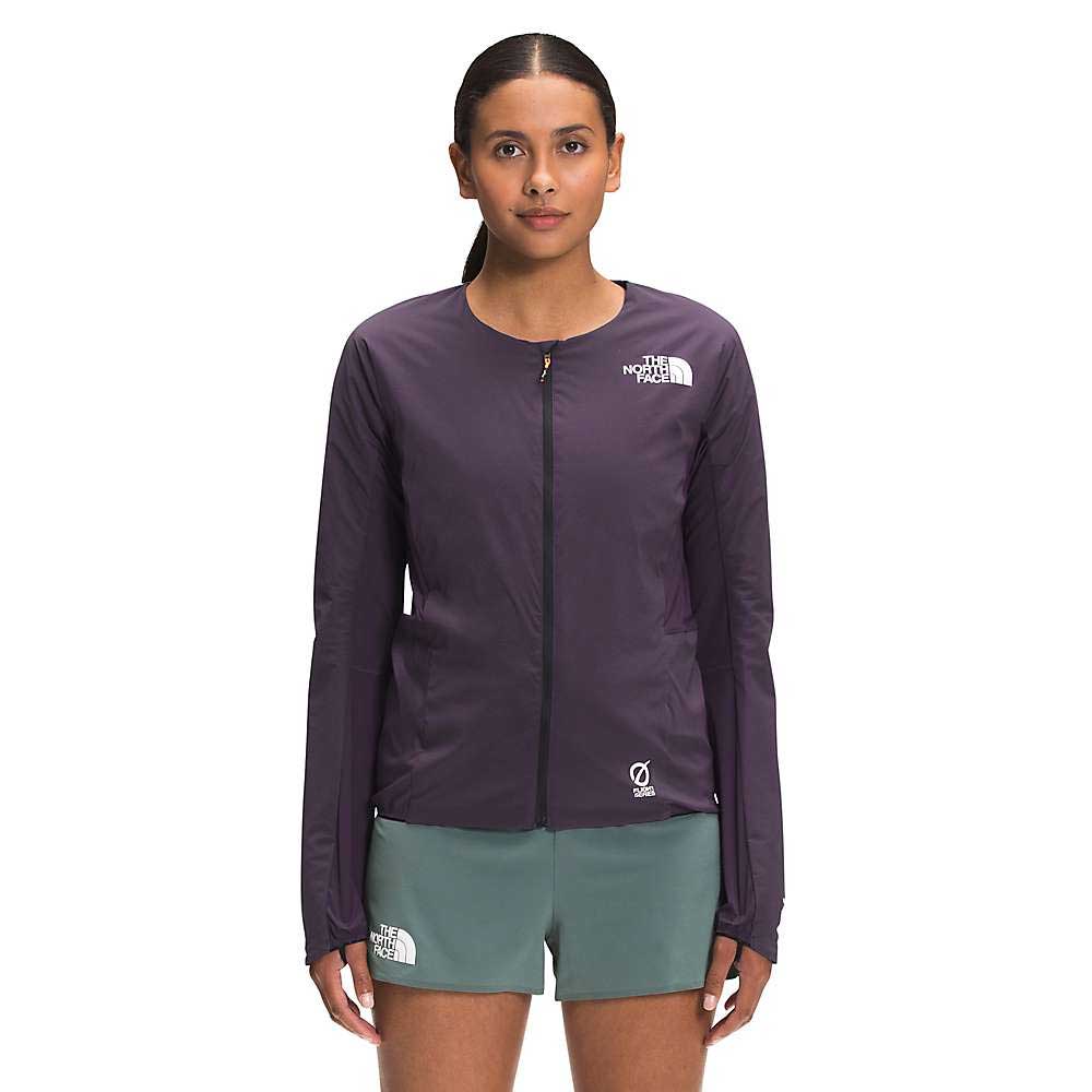 A woman stands facing forward in The North Face Womens Flight Ventrix Jacket, dark purple, with the logo visible, paired with green shorts against a plain white background.