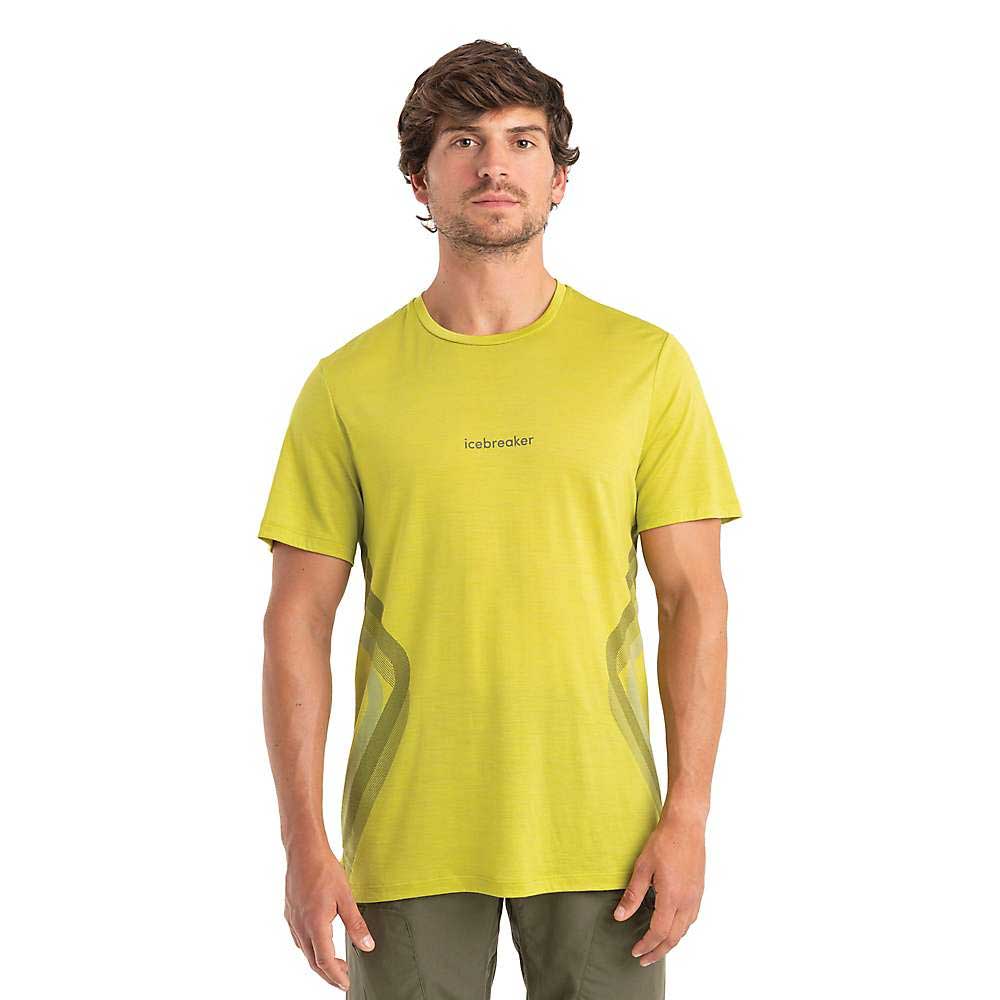 A man wearing the Icebreaker Mens Merino 125 Cool-Lite Sphere II Synergism SS Tee in light green and olive pants stands facing forward against a plain white background.
