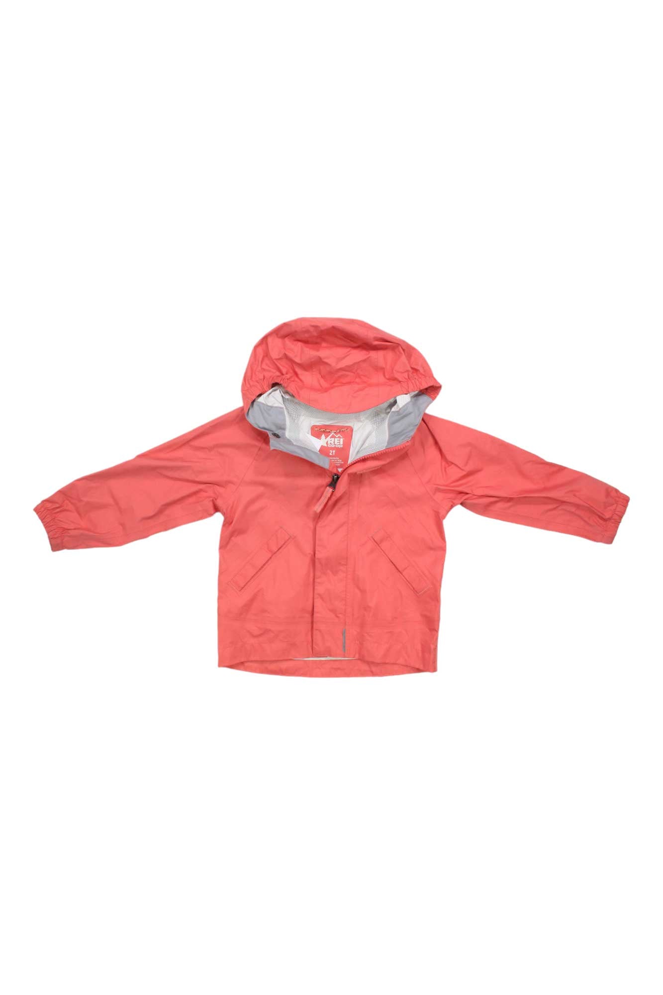 The Rainwall Rain Jacket - Kids, shown in bright coral pink and laid flat with arms extended, is waterproof with a hood, front zipper plus velcro flap, and elastic cuffs—ideal for kids' rainy day outdoor adventures.