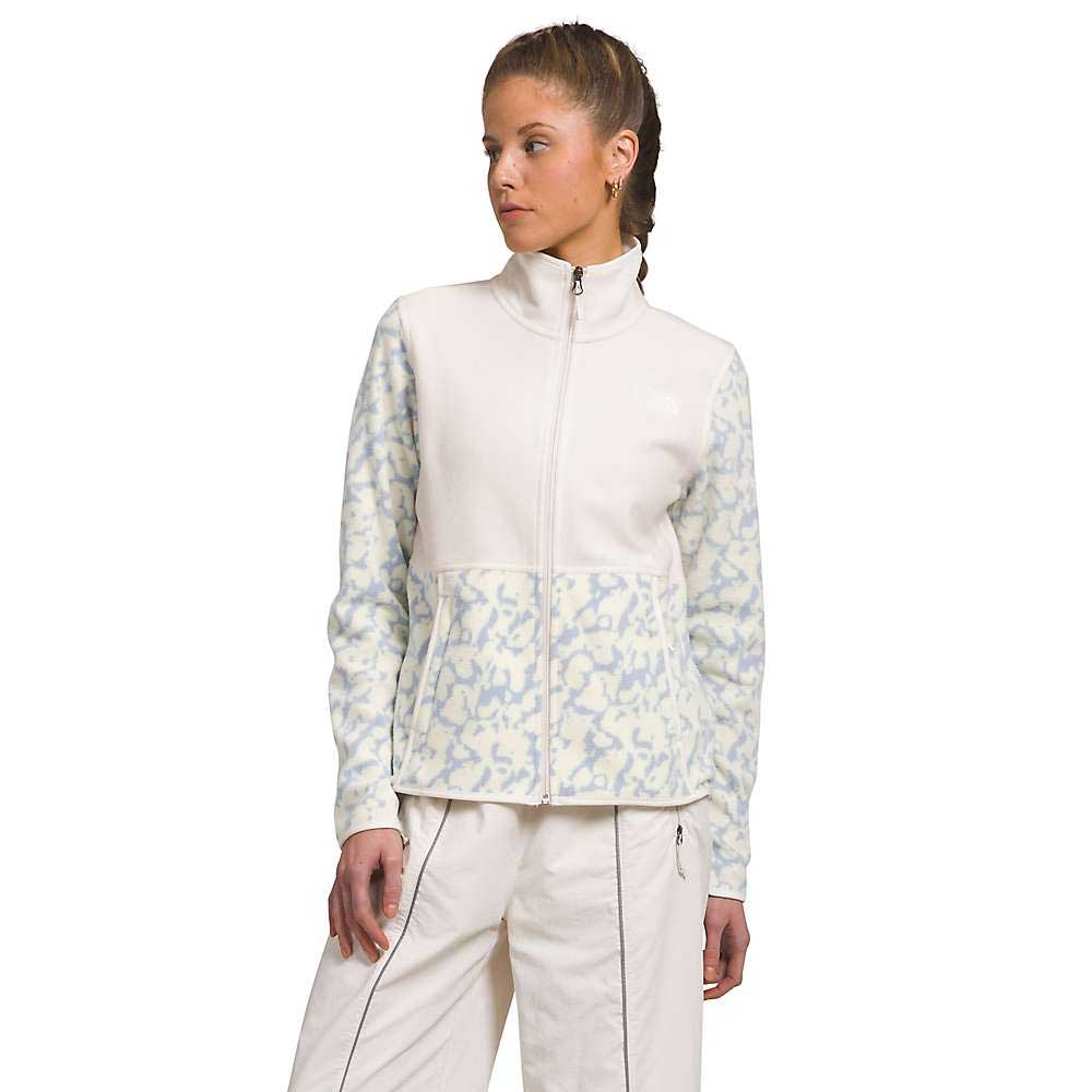A woman wearing The North Face Womens Alpine Polartec 100 Jacket with a high collar and subtle animal print sleeves, paired with light pants, stands turned slightly to the side against a plain white background.