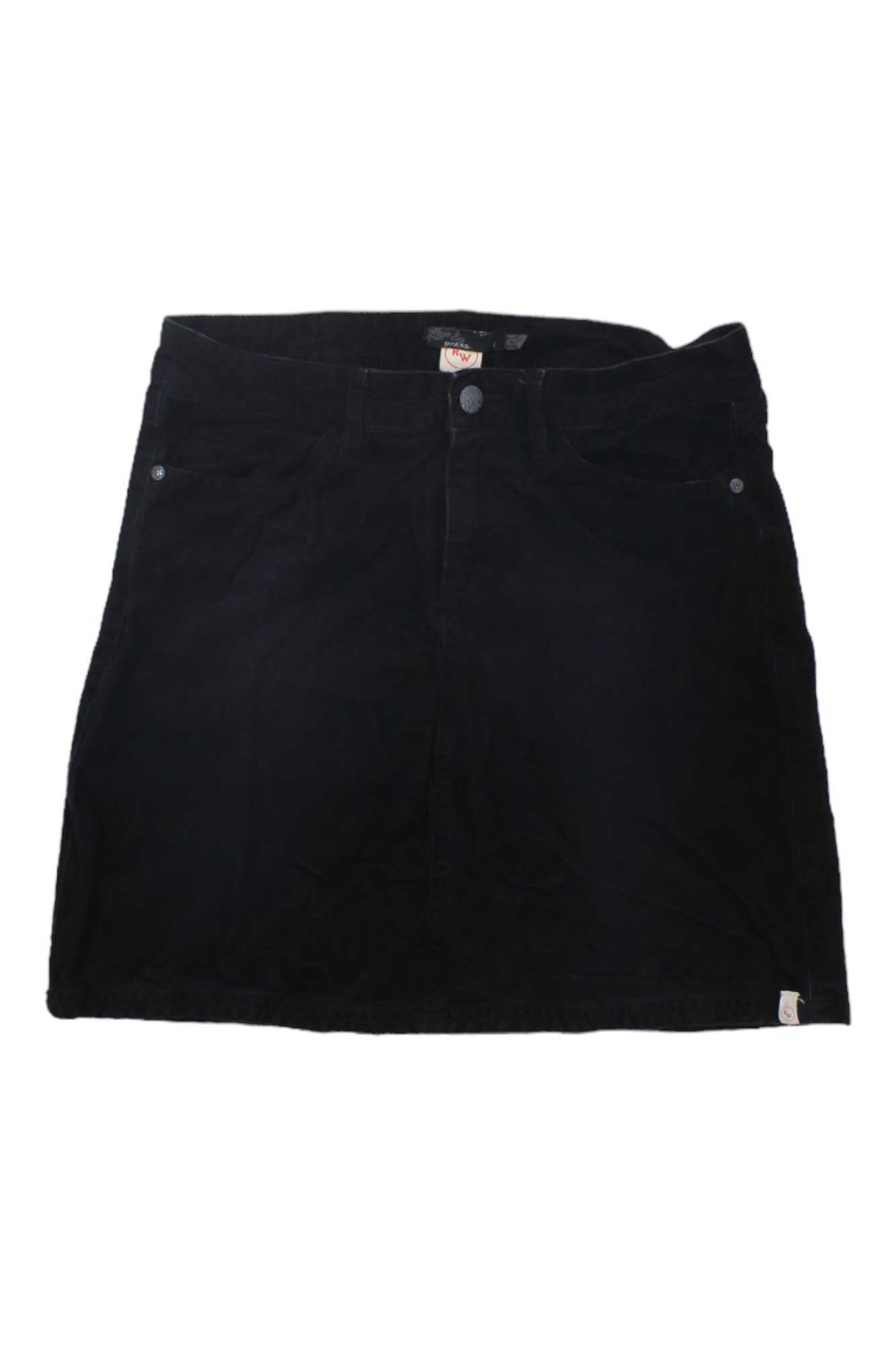 The Trista Corduroy Skirt is a black, knee-length A-line skirt featuring front pockets and a button waistband, shown laid flat on a white background.