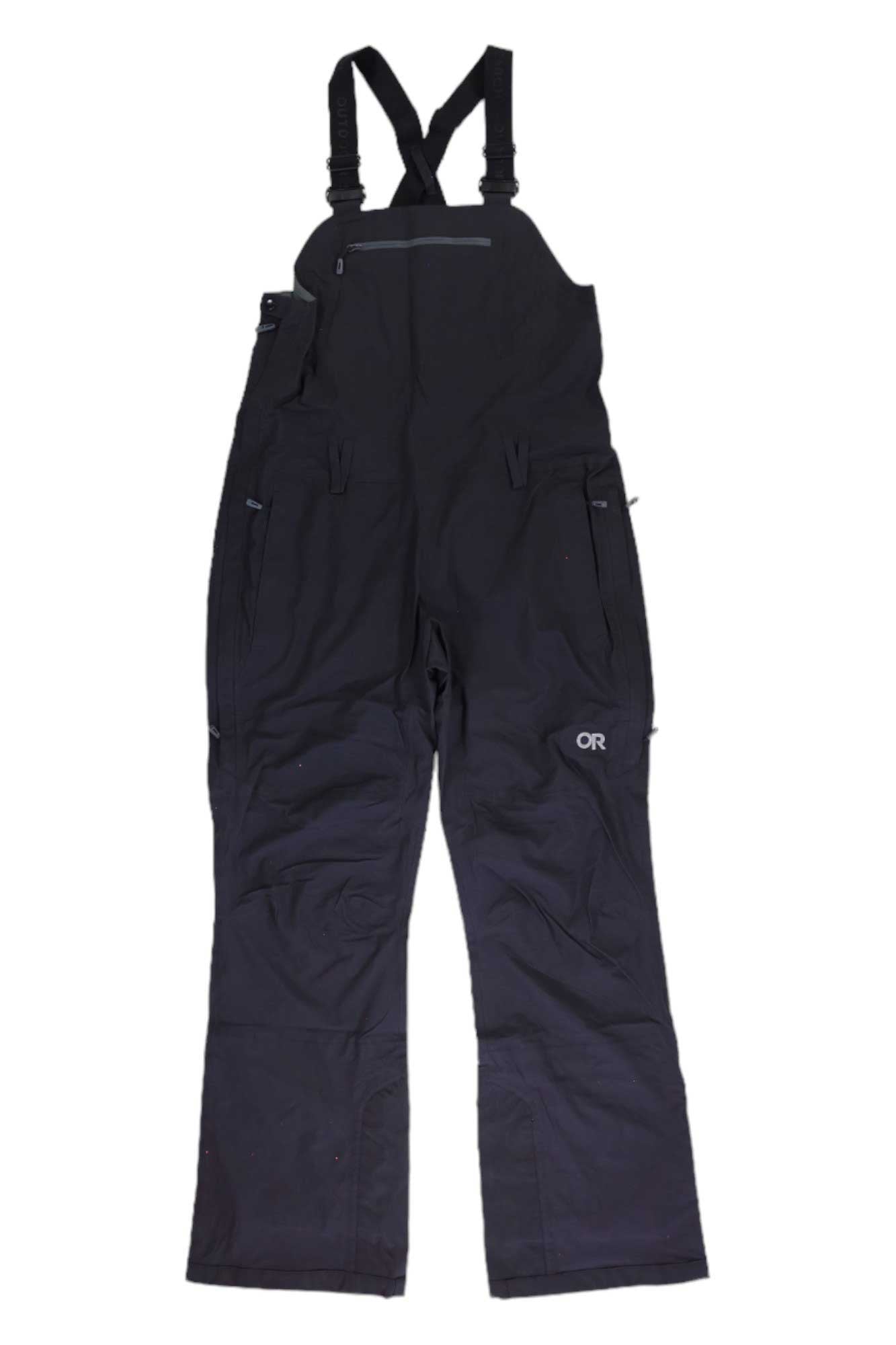 The Outdoor Research Women's Carbide Bib, shown flat on a white background, is a black waterproof overall with adjustable shoulder straps, multiple zippered pockets, and the OR logo on the left thigh—perfect for snowsports.
