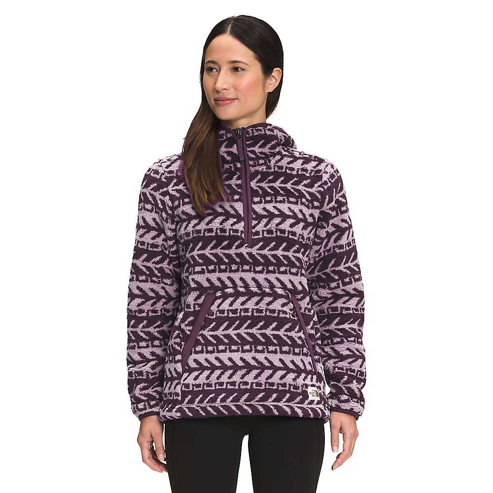 A woman stands facing forward, smiling slightly with her hands by her sides, wearing The North Face Women's Printed Campshire 2.0 Pullover Hoodie in a purple and lavender pattern with a high collar and front half-zip.