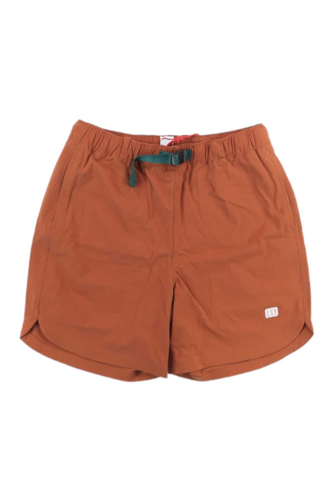 The Topo Designs Mens River 6 Inch Short features a rust color, elastic waistband with green drawstring, white logo on the left leg, quick-dry fabric, relaxed fit, and slight side slits at the hem.
