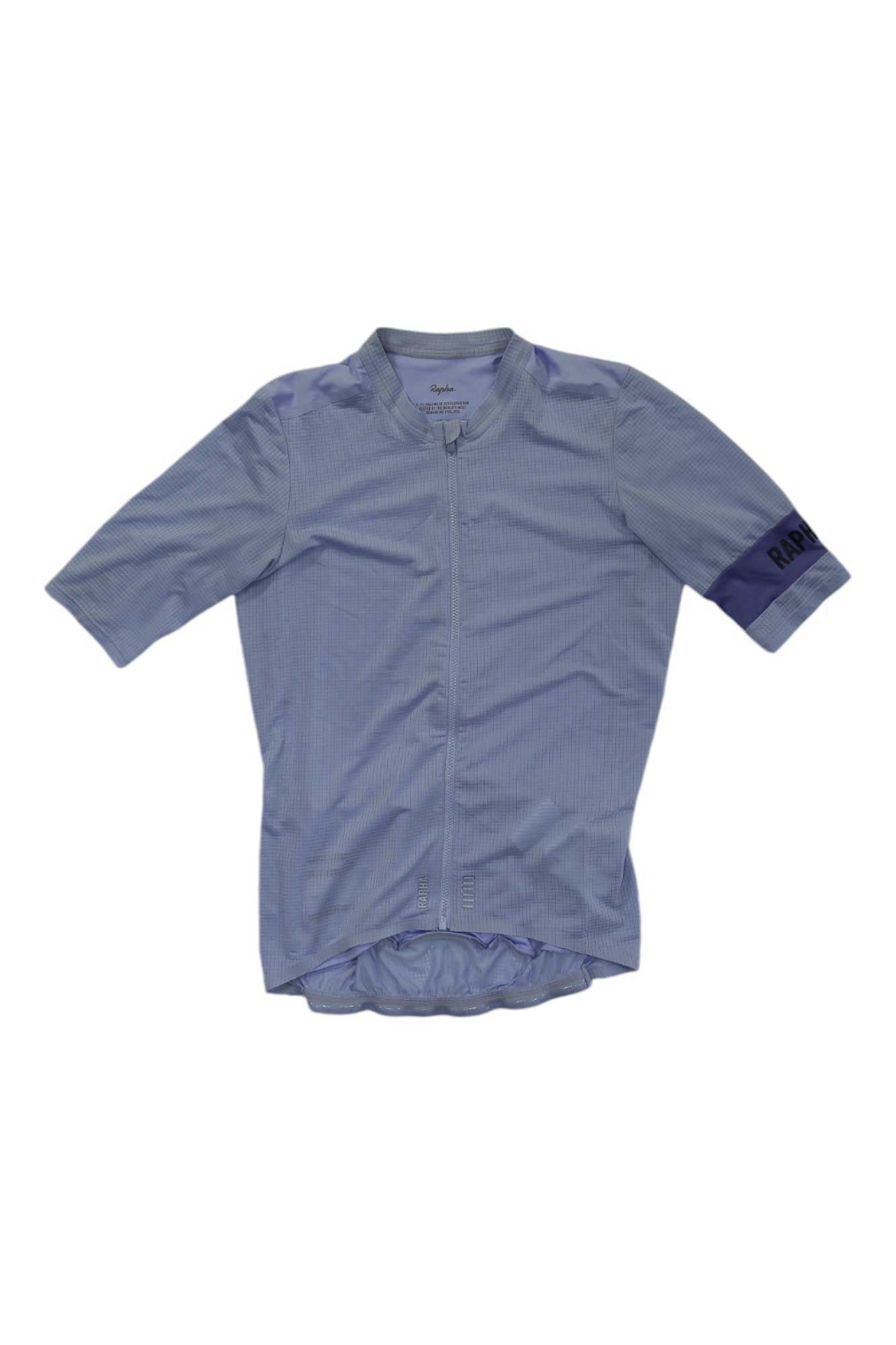 The Rapha Mens Pro Team Flyweight Jersey is light blue with short sleeves, a full front zipper, "Rapha" on the left sleeve, a subtle checkered pattern, elastic waist hem, and a lightweight design for cycling.