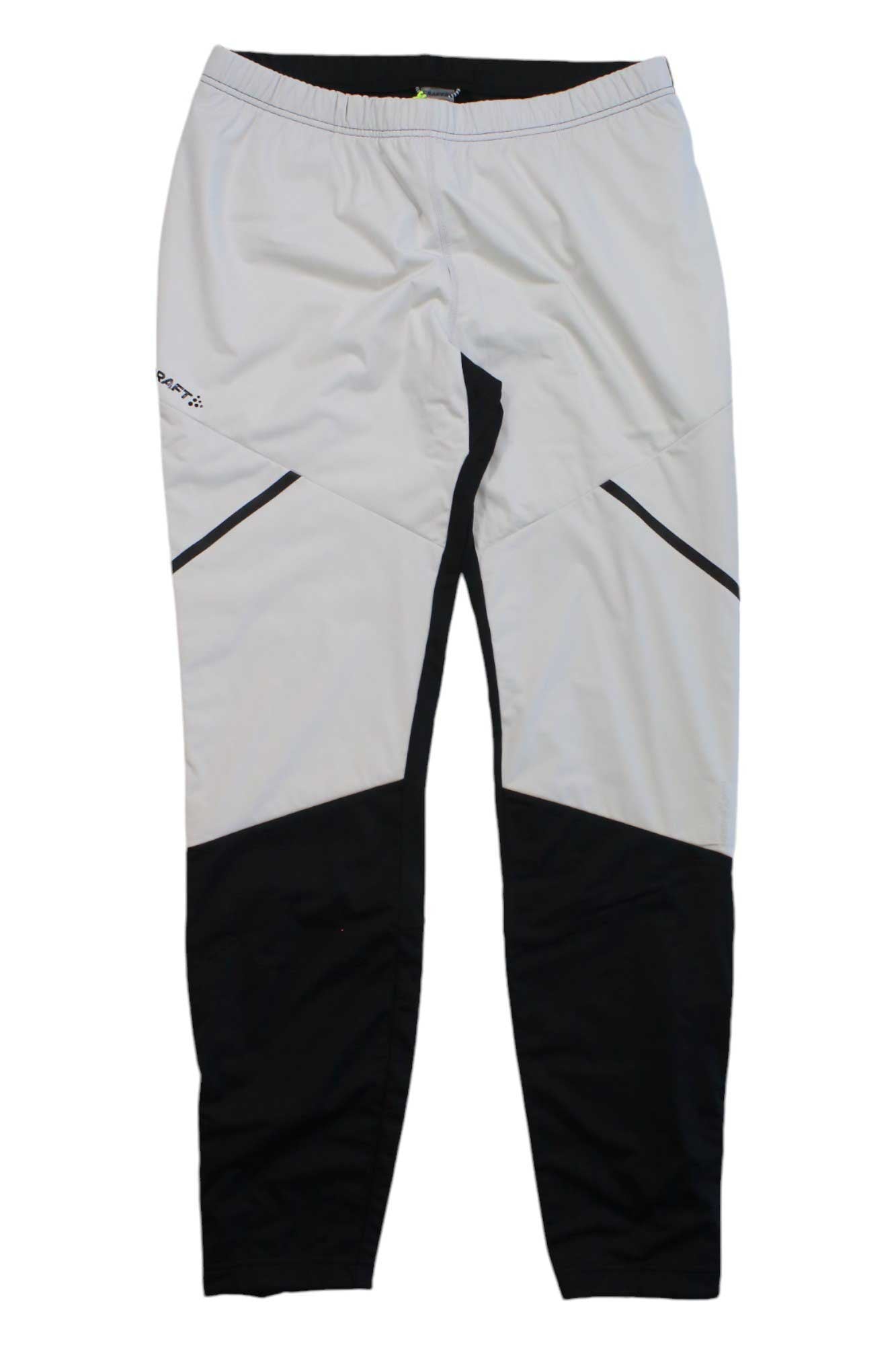 The Craft Sportswear Men's Glide Wind Tight features an elastic waistband, white design with black color blocking on the lower legs and angled thigh accents, all crafted from recycled sportswear material for eco-conscious comfort.