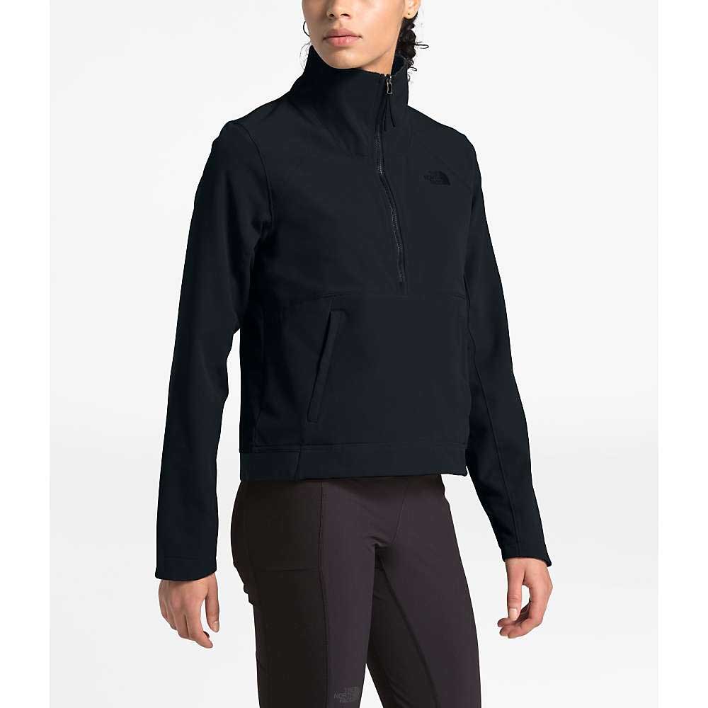 Wearing The North Face Womens Shelbe Raschel Pullover, a black fleece jacket featuring a high collar and side pockets, a person stands against a plain white background with head turned slightly to the side.