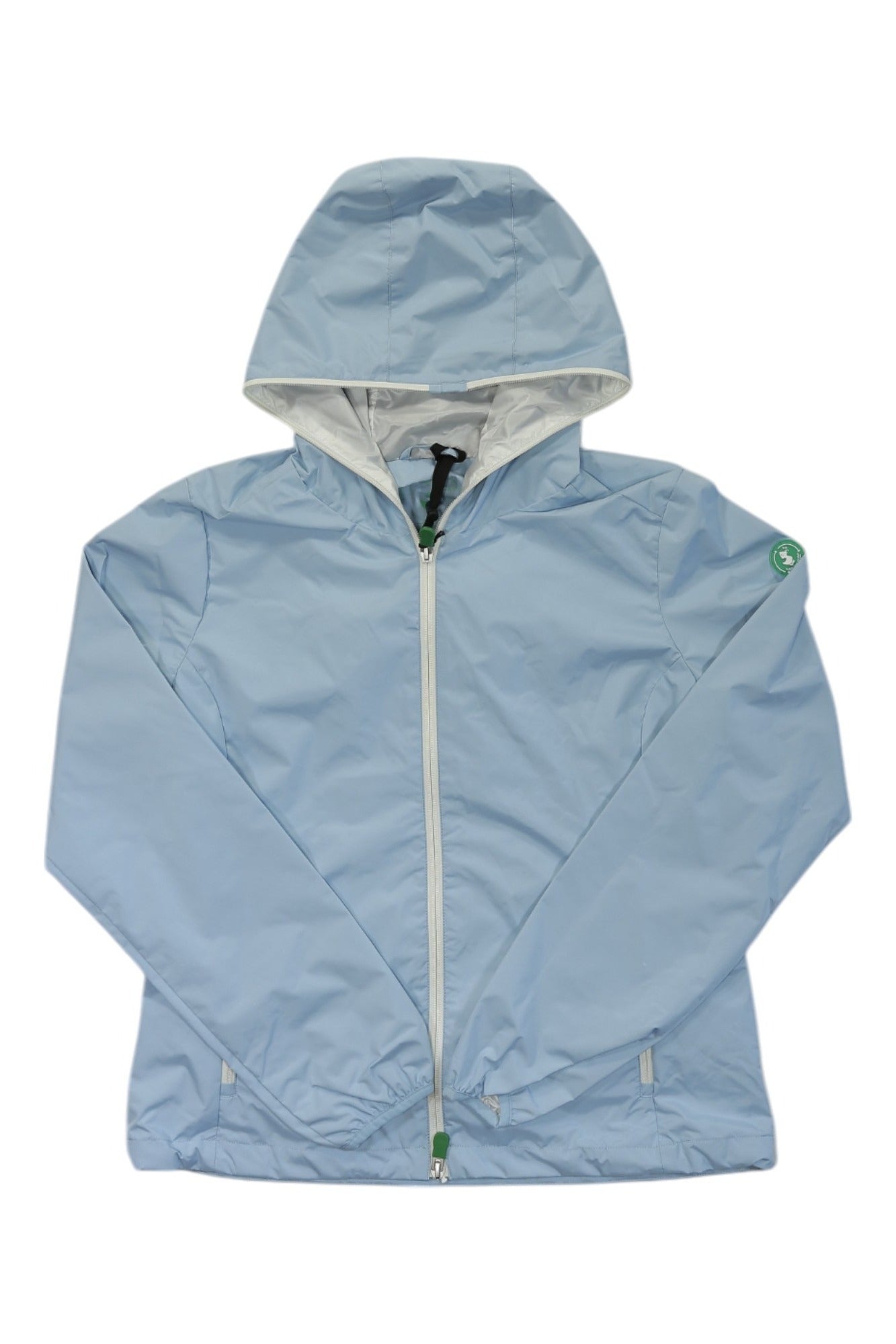 The Save The Duck Womens Stella Hooded Rain Jacket is light blue with a white zipper, elastic cuffs, and a small green logo patch on the left sleeve. This lightweight, minimalist hiking jacket is shown laid flat on a white background.
