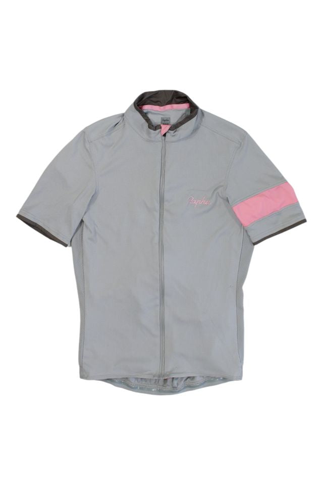The Rapha Mens Super Lightweight Jersey is a light gray short-sleeve cycling top with a front zipper, high collar, and pink stripe on the left sleeve. "Rapha" is embroidered in pink on the chest.