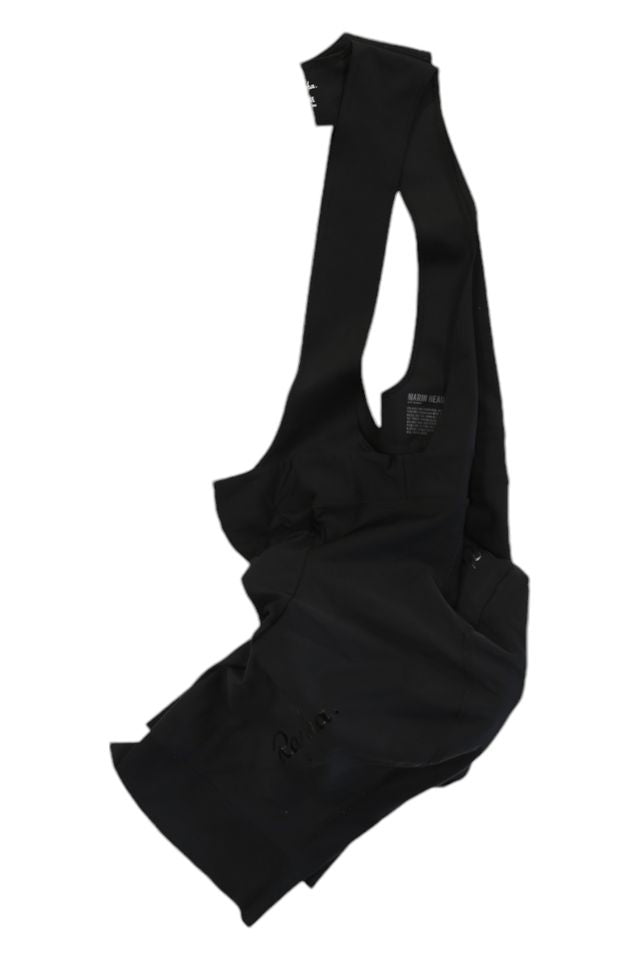 The Mens Bib Shorts are black, sleeveless cycling apparel with an asymmetrical, deconstructed design and overlapping fabric, shown laid flat on a white background.