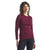 A woman with curly hair wears the Icebreaker Womens 200 Oasis LS Crewe and black pants, standing against a plain white background and smiling slightly.