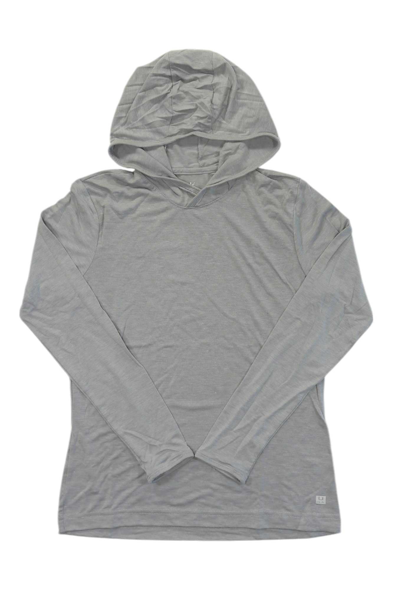 The Huk Womens Waypoint Hoodie is a light gray, long-sleeve fishing hoodie with a hood, shown laid flat on a white background with arms crossed at the wrists. Ideal for sun protection during any outdoor adventure.