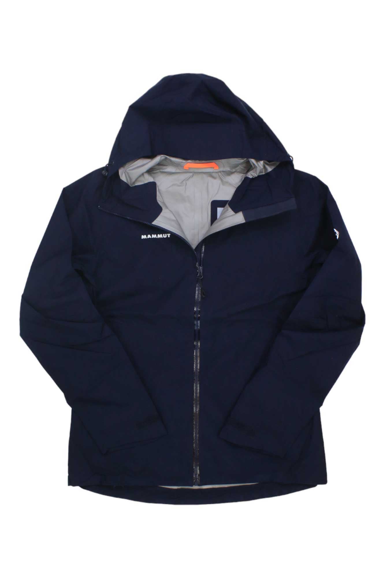 The Mammut Womens Convey Tour HS Hooded Jacket is a navy blue, lightweight, waterproof jacket for women with a hood, front zipper partially open to show light gray lining, and the white Mammut logo on the left chest.