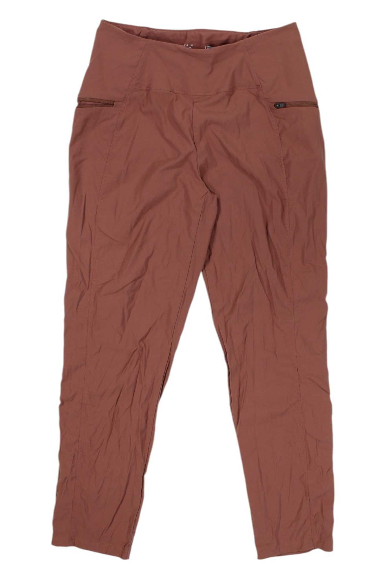 A pair of Mountain Hardwear Womens Dynama High Rise Pants in rust, featuring front zipper pockets and a slightly wrinkled finish, is laid flat against a white background.