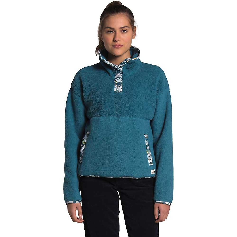 A person faces forward in The North Face Womens Liberty Cragmont Fleece 1/4 Zip Top with a Liberty of London print collar and cuffs, paired with black pants, standing against a plain white background.