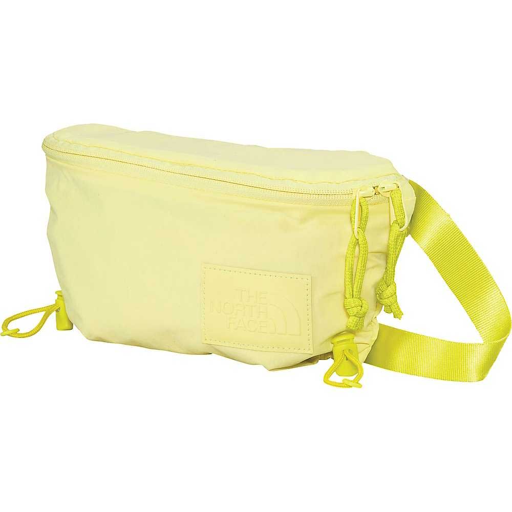 The North Face Women's Never Stop Lumbar Waist Pack is a light yellow waist pack made from recycled nylon with a zippered main compartment, adjustable strap, and front logo patch.