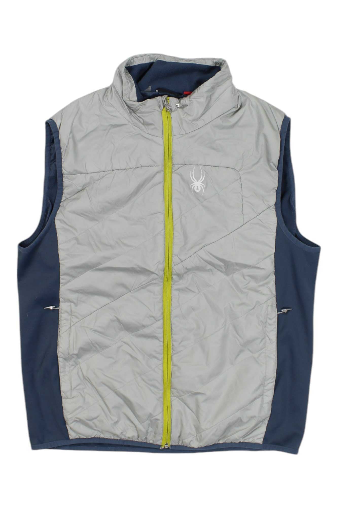 The Spyder Mens Exit Insulator Vest features a light gray front, navy blue sides and back, high collar, yellow zipper, and a white spider logo on the left chest—ideal for outdoor performance.