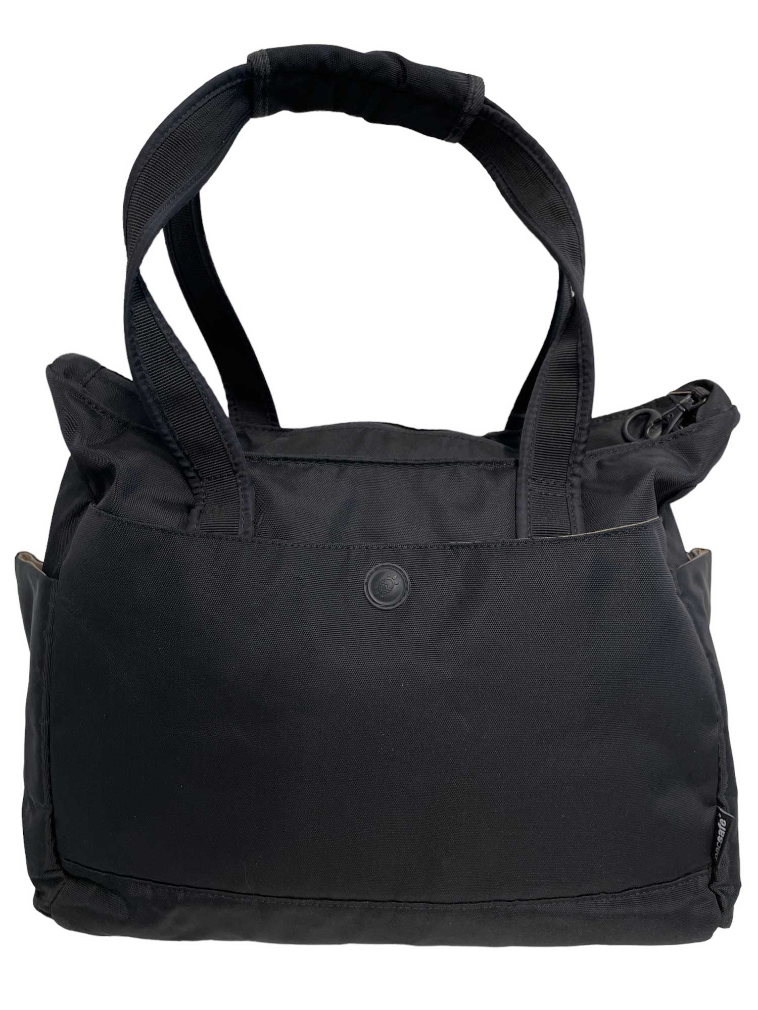 The Tote Safe 100 is a black fabric travel bag with two shoulder straps, front pocket with snap closure, spacious main compartment, zipper security, and a minimalist design.
