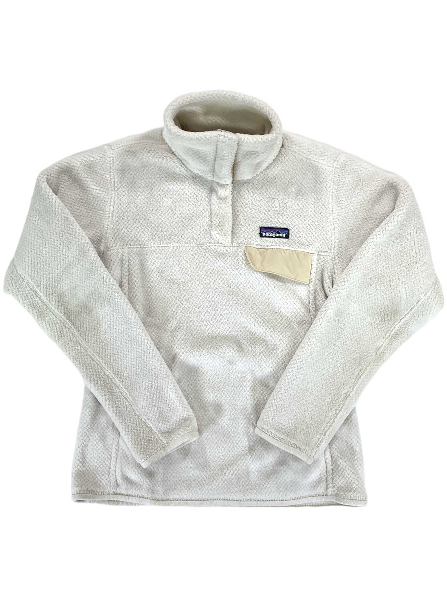 The Women's Re-Tool Snap-T Pullover by Patagonia is a cream-colored, long-sleeve Polartec fleece with a high collar, snap buttons, and a beige chest pocket featuring the Patagonia logo patch. It is shown laid flat on a white background.
