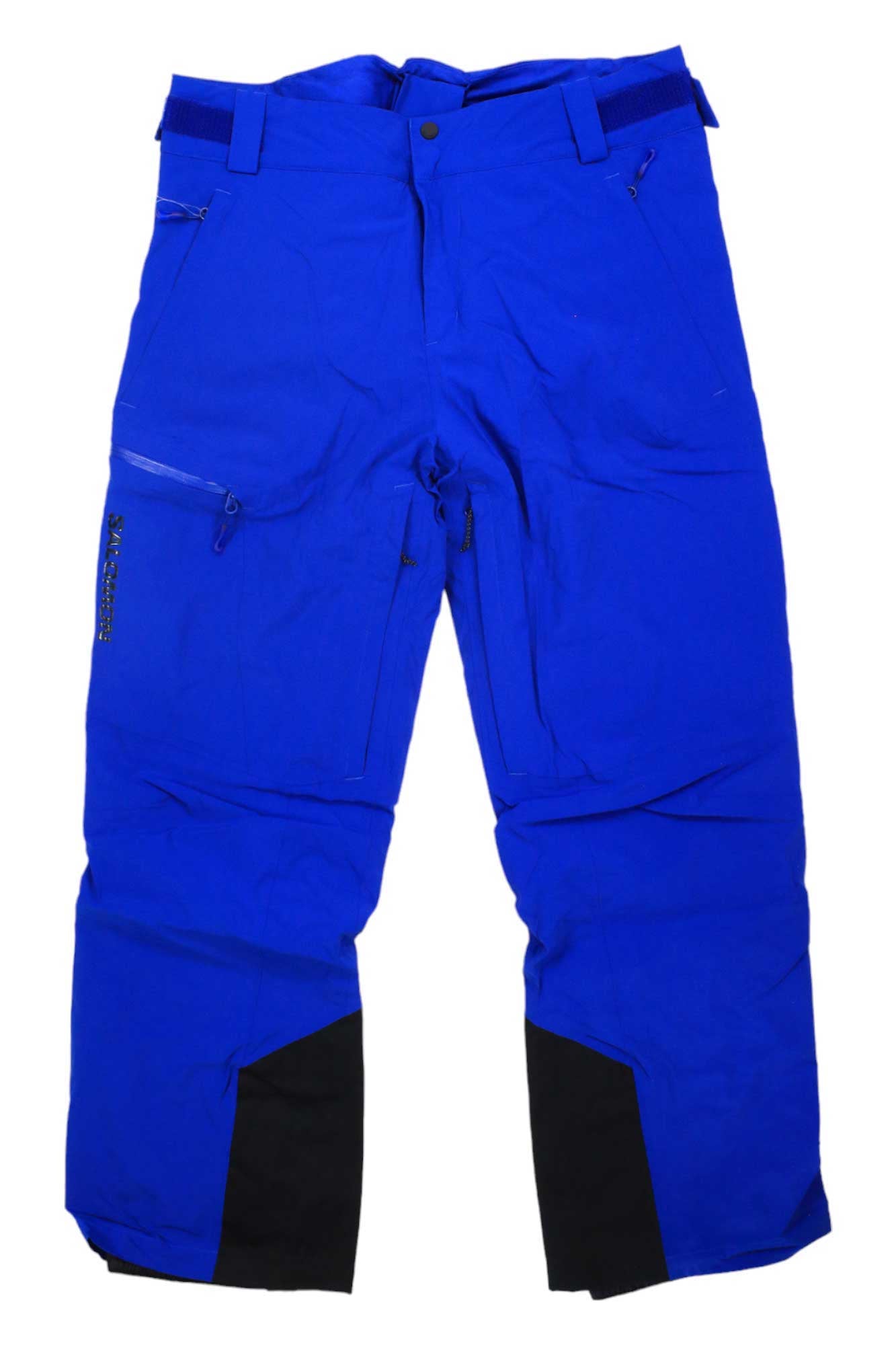 The Salomon Men's Brilliant Pant—waterproof insulated ski pants in bright blue with black reinforced inner ankle patches, zippered pockets, and adjustable waist tabs—are shown laid flat on a white background.