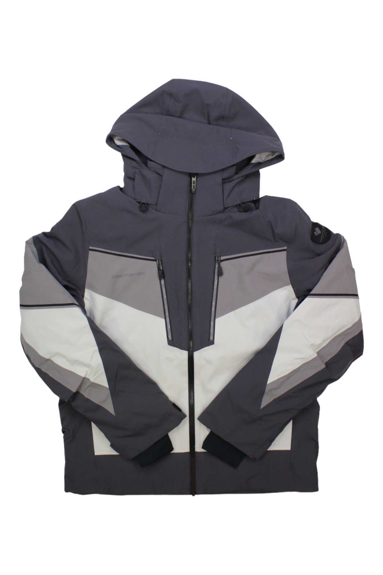 The Obermeyer Mens Charger Jacket is a gray ski jacket with white and light gray geometric patterns, a front zipper, two zippered chest pockets, black cuffs, PrimaLoft Black Eco insulation, waterproof fabric, and a modern padded design.