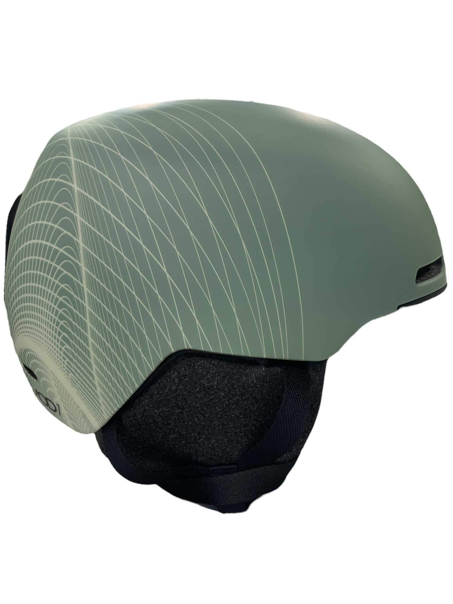The Oakley Mod1 Helmet features a matte green finish, sleek geometric white line patterns, black ear covers, and a smooth skate-style shape for a modern look on the slopes.