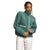 A person with braided hair wears The North Face Womens Cragmont Fleece Jacket in green with light green trim and buttons, featuring two front pockets, paired with white pants, standing against a plain white background.