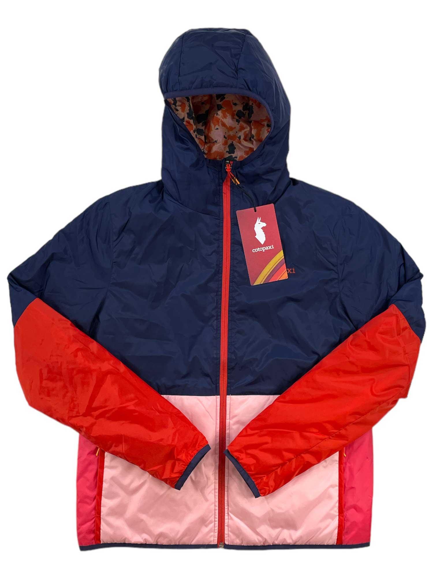 The Cotopaxi Womens Teca Calido Hooded Printed Jacket is a color-blocked women’s jacket with recycled insulation, navy blue top, red sleeves, pink lower panels, front zipper, and a red tag with a white rabbit logo on the zipper pull.