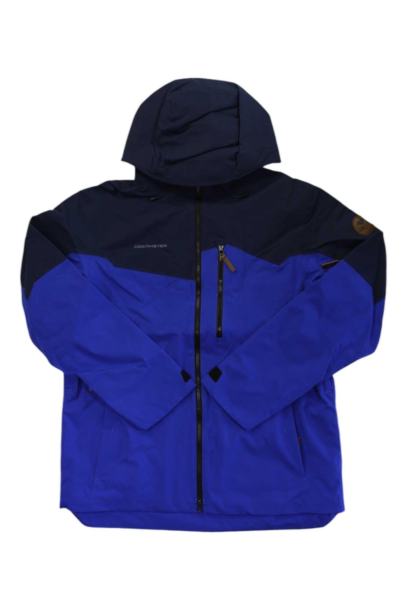 The Obermeyer Mens Chandler Shell Jacket is a blue and black water-resistant shell for men, featuring a front zipper, zippered chest pocket, upper sleeve patch, long sleeves, and a high collar.
