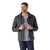 A man wears a dark gray Smartwool Mens Smartloft Shirt Jacket over a light gray graphic tee and blue jeans, facing slightly right, holding his jacket edges and smiling against a white background.
