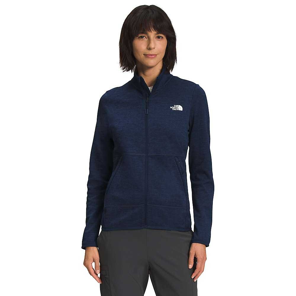A woman with short dark hair stands against a white background, wearing gray pants and a navy blue The North Face Women's Canyonlands Full Zip Jacket, her arms relaxed by her sides.