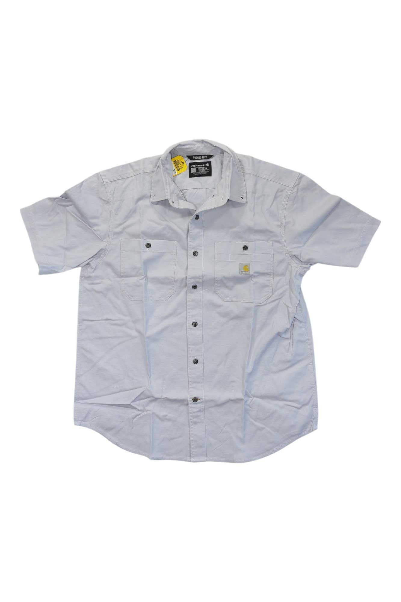 The Carhartt Men's Rugged Flex Rigby SS Work Shirt is light gray with short sleeves, two chest pockets (one with a small yellow and white logo patch), and features a black and yellow tag inside the collar. The shirt appears slightly wrinkled.