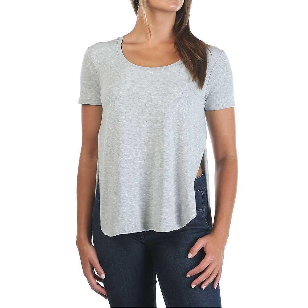A woman wears the Moosejaw Womens Lakeside Crossover Tee in light gray with side slits and dark blue jeans, posing with one hand on her hip against a plain white background.