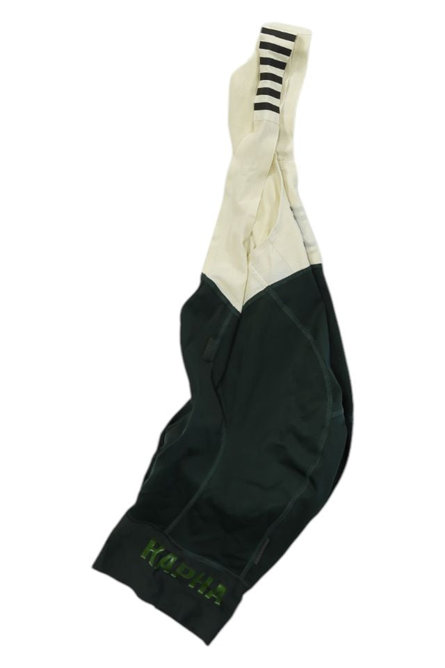 Dark green and cream cycling bib shorts with black-striped shoulder strap and green "KAPELMUUR" on the leg, featuring a race-grade chamois—ideal for enthusiasts of Rapha Mens Pro Team Bib Shorts II - Regular.