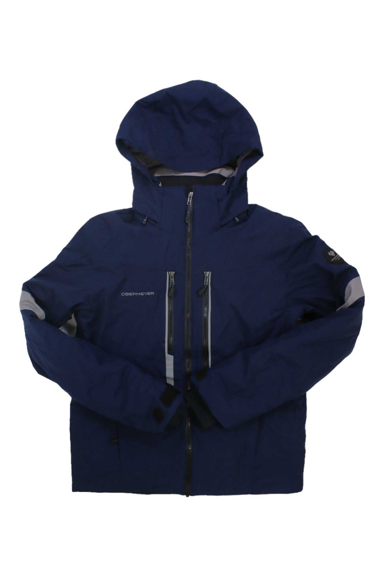 The Obermeyer Mens Fall Line Jacket is a navy blue ski jacket with black zippers, long sleeves, and a high collar. It’s waterproof, insulated with PrimaLoft, and features two vertical chest pockets plus logos on the left chest and arm.