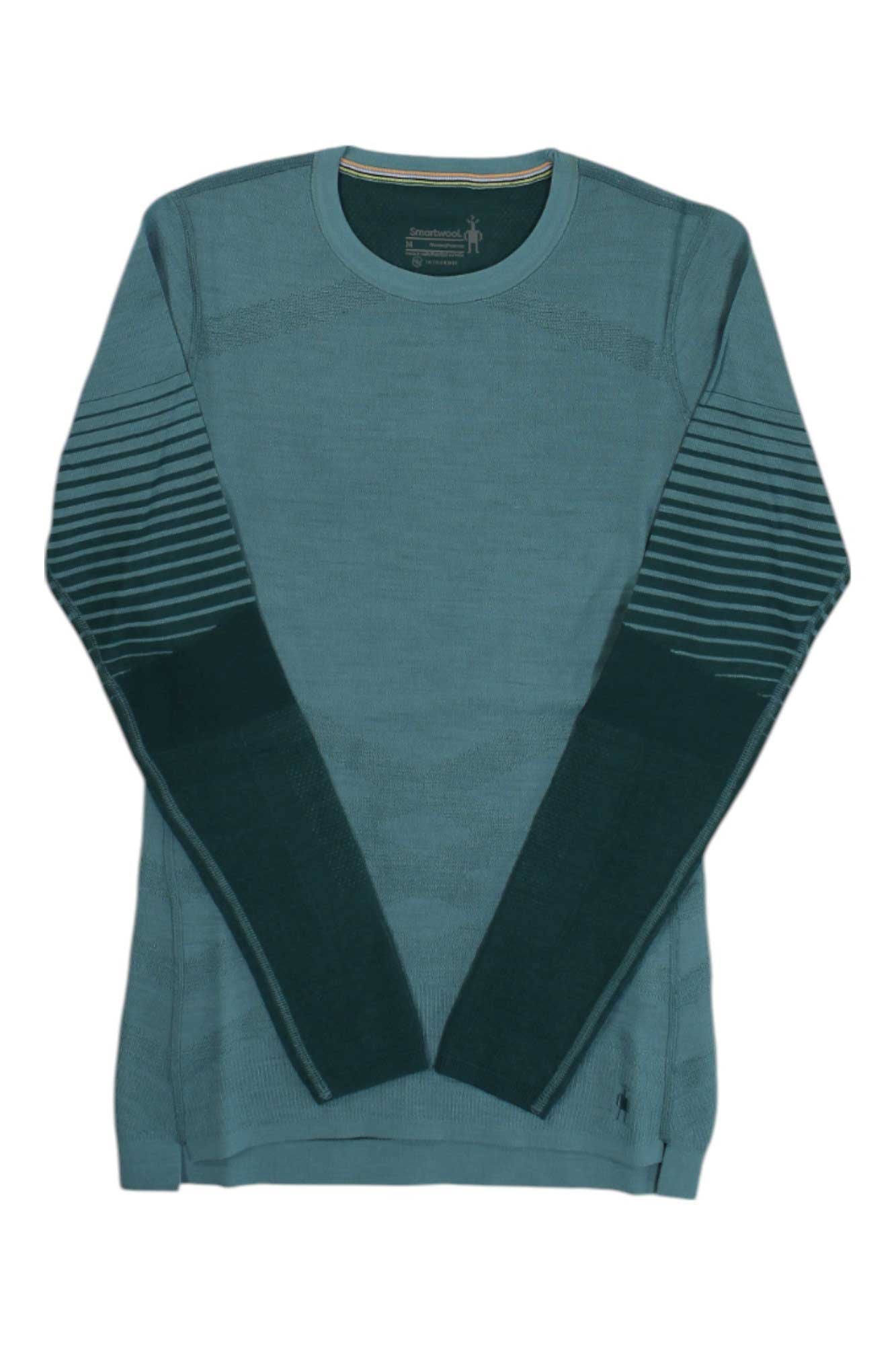 The Smartwool Women's Intraknit Thermal Merino Pattern Crew Base Layer Top is a teal, long-sleeve sweater with dark green sleeves and light stripes on the upper arms. It features a round neckline and offers a slim, cozy fit.